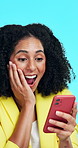 Businesswoman, surprise and wow in studio with phone, announcement or good news for marketing agency. Happy, person and shock with tech, online notification or advertising success on blue background.