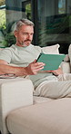 Scroll, online and man with tablet in lounge, relax and reading ebook on web or comfortable on couch. Browse, novel and mature person with tech for entertainment, home and chill with app subscription