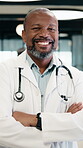 Doctor, face and black man with medical career, happiness or confident in hospital hallway. Smile, portrait and mature physician with arms crossed for healthcare service, trust or job excellence