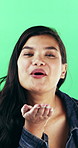 Face, woman and blowing kiss in studio for love, care and flirt emoji on green background. Air, happy person and romance gesture for connection, affection and show attraction on valentines day