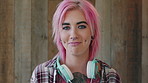 Face, woman and punk style by wood background with tattoo, headphones and pink hair for edgy aesthetic. Happy, person and alternative fashion with audio tech, piercings and makeup for individuality.