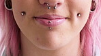 Woman, closeup and smile with piercing in lips, septum and and pink hair with earrings for style. Person, mouth and hairstyle with stud in cheeks, facial beauty or confidence with body art on skin