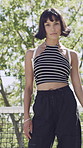 Woman, face and confident with streetwear for fashion, college student or outdoor with trendy outfit. University, tennis net and person with confidence, attitude and serious with stylish clothes