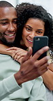 African couple, hug and chat with phone for social media, meme or bonding in living room of home. Man, woman and relax with smile on tech for communication, embrace and love on sofa with gossip story