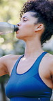 Woman, fitness and drinking with water in park for hydration, natural sustainability or break. Active, female person or thirst with mineral liquid or bottle for workout recovery or outdoor rest