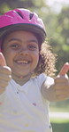 Roller skating, thumbs up and face of child in nature for fitness, exercise or balance on holiday. Dance, helmet and portrait of girl kid outdoor in park with hobby, activity or workout on vacation.