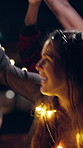 Fun, dance and woman with lights at festival, glow or listening to music entertainment with friends. Dark, event and people with smile for celebration, bokeh and social gathering for festive season