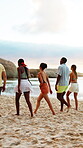 Friends, walk and group at beach for holiday, talk and travel together in nature on weekend getaway. Outdoor, space and exploration on summer vacation, back and bonding with people on sea adventure