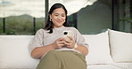Relax, reading and Asian woman with phone on couch, check notification and watch social media video. Online conversation, chill or person with smile for blog post by home, mobile or browsing internet