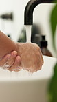 Water, bathroom and person washing hands in home for health, self care or wellness by sink. Soap foam, disinfection and cleaning skin for removal of bacteria, germs or dirt for hygiene in house.