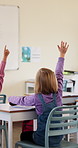 Education, child and raised hand for question in classroom, knowledge and growth development. Girl, learning and student with quiz answer at lesson, asking and participation from back at school