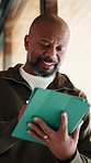 Tablet, reading and black man in home with research for budget planning, finance or savings. Digital technology, online and mature African male person with blog on financial investment in house.