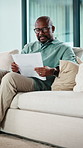 Black man, smile and documents for taxes in home on sofa, glasses and financial review with budget. African person, happy and paperwork with bills, admin or insight on with asset management in house