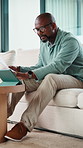 Black man, tablet and documents for taxes in home on sofa, typing and financial review with budget. African person, tech and paperwork with bills, admin and click on fintech application at apartment