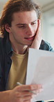 Document, finance and man in home with stress for debt crisis, bankruptcy and rent increase. Paperwork, expenses and person at house with tax cost, bad credit and reading information for bills