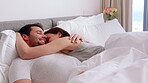 Couple, cuddle and bonding on bed in home, love and affection for partner or commitment for marriage. Happy people, resting and embrace with spouse in bedroom, man and laugh with woman and romance