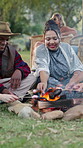 Outdoor, festival and friends with marshmallows, fire and gathering with snack on weekend in nature. Happy people, relax and roasting food at social event, together and bonding on festive season