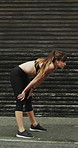 Running, earphones and break with woman in city for streaming service, workout playlist and fitness. Runner podcast, recovery and wellness with female person outdoor for training, stop and cardio