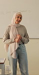 Happy, teacher and Muslim woman in classroom for education, knowledge and conversation with students. School, educator and person with hijab, talk and teaching learners with smile and explanation