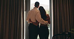 Back, hug and view with homeowner couple at window together for relationship goals or success. Celebration, love and security with happy people in apartment for bond, mortgage or property investment