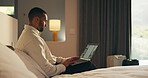 Business trip, laptop and remote work with man in hotel room for planning or research. Computer, scrolling and typing with corporate employee on bed in lodge for accommodation or hospitality