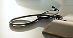 Healthcare, notebook and stethoscope on desk in hospital for heart beat monitor, schedule reminder or wellness. Medical report, cardiology or research with doctors equipment in clinic or empty office