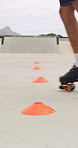 Roller skates, park and cones for practice with legs, balance and outdoor in summer in urban town. Person, feet and wheels with marker, beacons and coordination with training on concrete in city