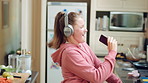 Audio, headphones and child dance in home with energy, streaming service and singing song. Excited girl, music and moving at kitchen with phone for sound, freedom and listening to radio with rhythm