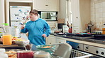 Dancing, singing and happy man with spoon in kitchen for playful cooking or fun meal prep in home. Karaoke, energy or male person with down syndrome for music, audio streaming or podcast in house