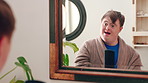 Mirror, happy and teenager brushing hair in bathroom for grooming or self care in home. Goofy, reflection and male person with down syndrome in house for getting ready in morning with hairstyle.