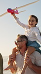 Father, plane and girl on shoulder at beach with family, fun and bonding on vacation in summer. People, children and parents with connection, happy and flight with toy on walk for seaside holiday