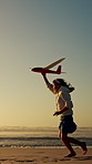 Happy, girl and running with aeroplane on beach sunset for summer holiday, weekend or vacation. Playful, child or kid playing with flying toy or waves on ocean coast for fun outdoor childhood or trip