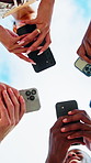 People, hands and huddle with phone for network, data sync or sharing app below blue sky in nature. Low angle, community or group of friends in circle with smartphone for connection or social media