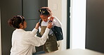 Mother, helping and child with bag at house for getting ready, morning routine and back to school. Woman, dressing and daughter for neat appearance, punctuality and backpack for learning preparation
