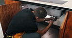 Man, plumber and wrench in kitchen for maintenance, repair service and sink leak in apartment. Handyman, contractor and fixing pipe with tools for drainage, home improvement and blue collar labor