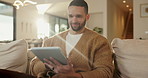 Tablet, relax and man in home, typing or online search for news website with app at living room. Technology, smile and person on sofa for reading article with newsletter, ebook or internet blog