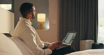 Business trip, laptop and thinking with man in hotel room for planning or research. Computer, remote work and typing with corporate employee on bed in lodge for accommodation, hospitality or ideas