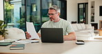 Mature, man and documents with laptop for finance, budget planning or checking expenses in home. Male person, computer and financial assessment with papers for investment, invoices or bills in house