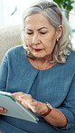 Tablet, scroll and senior woman in home for morning news, reading information or thinking in retirement. Tech, relax and elderly person in living room for article story, online search and reflection