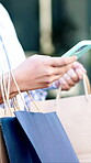Phone, fashion and hands with shopping bags in city, browsing or searching for discount offer on web. Texting, outdoor and person with mobile, purchase and scroll sale promotion on social media app