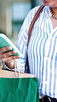 Phone, fashion and hands with shopping bags, outdoor or searching for discount deals on social media. Purchase, online and person with mobile, walking and scroll sale promotion on website in city