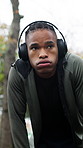 Fatigue, fitness and sweat with black man outdoor for sports development or progress. Headphones, running and streaming with tired person in nature for commitment or dedication to health and wellness