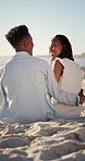 Hug, black couple and relax on holiday at beach for romantic getaway, bonding and conversation. Support, love or happy people with embrace on sand for summer vacation, talking or healthy relationship