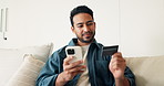 Phone, credit card and man on sofa in home with online shopping, ecommerce or purchase on mobile app. Relax, debit and male person with cellphone for order on website in living room at apartment.