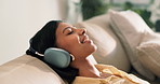 Headphones, happy and woman on sofa in home with music, playlist or podcast online with relax. Calm, audio tech and female person chilling with streaming of album on weekend in living room at house.