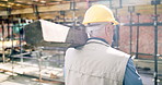 Mature, man or architect walking with concrete on construction site for building material. Back view, male person or contractor with equipment or safety gear for structure or architecture development