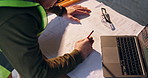 Person, hands or architect with blueprint or laptop on construction site for building or planning. Top view, civil engineer or contractor writing with floor layout or computer for architecture design