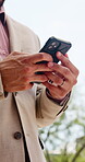 Employee, typing and hands with phone, outdoor and chatting with contact for real estate investment. Low angle, message and business person with mobile, realtor and communication on social media app
