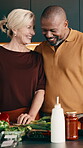 Cooking, funny and smile of interracial couple in kitchen together for diet or healthy eating. Food, ingredients and laugh with mature people at counter in apartment for meal preparation or nutrition