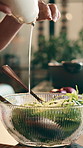 Person, hands and bowl with salad dressing in kitchen for vegan meal, preparation or healthy recipe. Vegetarian, chef or tossing food with liquid seasoning, lettuce or vegetables for nutrition flavor